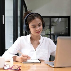 asian woman interpreter write translation from foreign language to english listen to audio record in