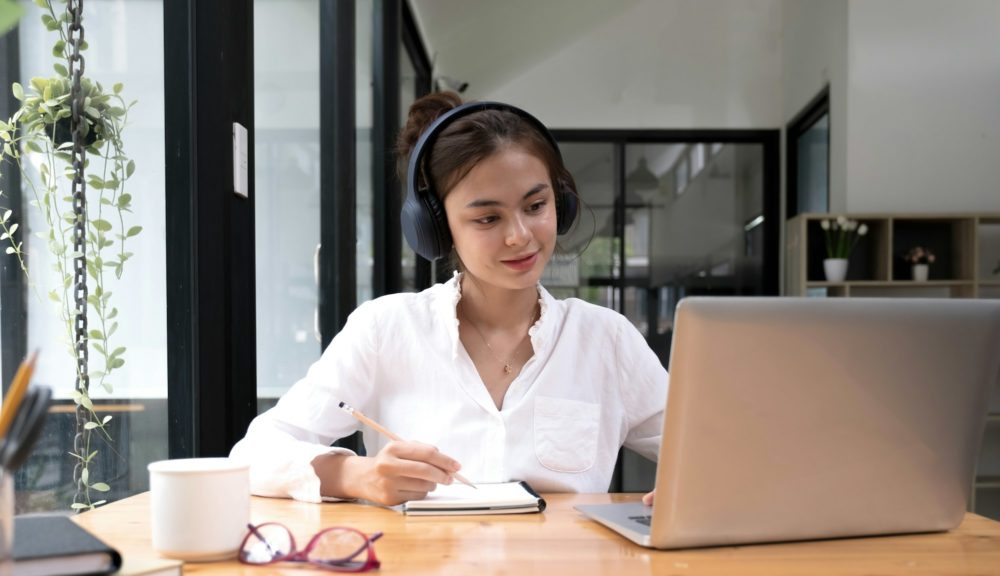 asian woman interpreter write translation from foreign language to english listen to audio record in