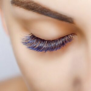 Eyelash Extension Procedure. Woman Eye with Long Blue Eyelashes. Ombre effect. Close up, selective