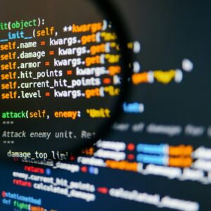 Program code on computer display in magnifying glass. Close-up