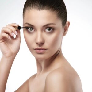 Woman applying mascara on eyelashes